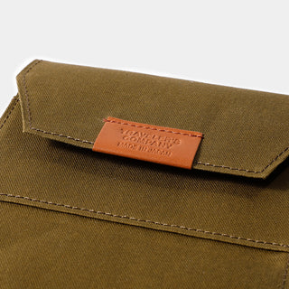 Olive cotton passport case with orange leather logo patch and contrast topstitching