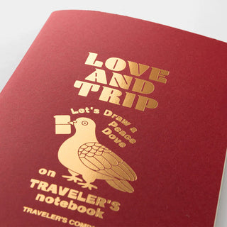 Close-up of red Traveler's notebook refill cover with gold bird and Love and Trip title