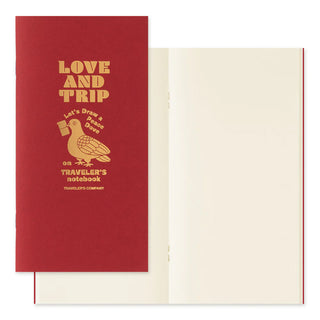 Traveler's notebook refill booklet open, showing cream blank pages and red cover