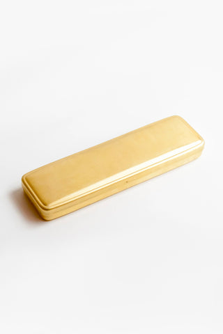 Gold brass pen case with rounded rectangular shape, closed lid