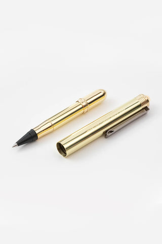 Brass rollerball pen with cap and exposed black tip on white background.