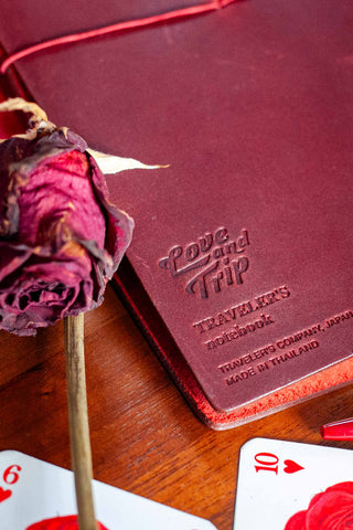 Embossed LOVE AND TRIP leather journal cover in deep red with cord tie