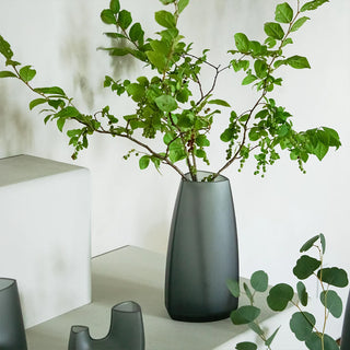 Dark green-gray tapered glass vase with leafy branches