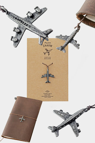 Pewter airplane charm on leather strap, hanging from a notebook cover.