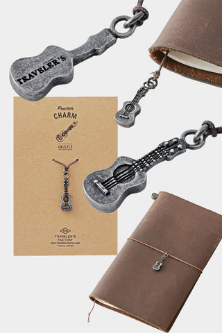 Pewter ukulele charm attached to brown leather journal with chain