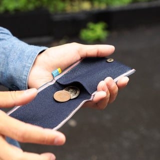 Dark blue denim coin purse with snap clasp, holding coins