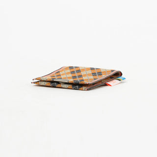 Folded fabric coin purse with orange and cream check argyle pattern and metal clasp
