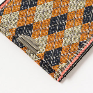 Corner close-up of coin purse with navy, orange, and cream geometric weave and metal clasp