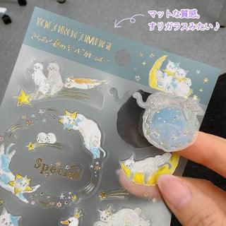 Close-up of clear gold-foil celestial stickers featuring a moon, star shapes, and planet