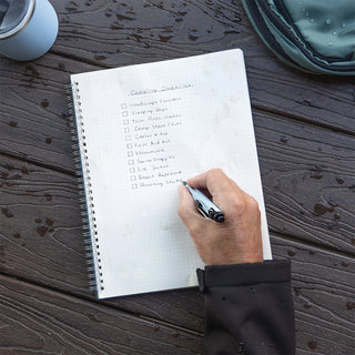 Dark AirPress ballpoint pen writing in spiral notebook