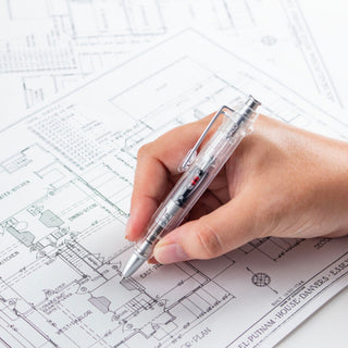 Transparent ballpoint pen in hand over architectural blueprint