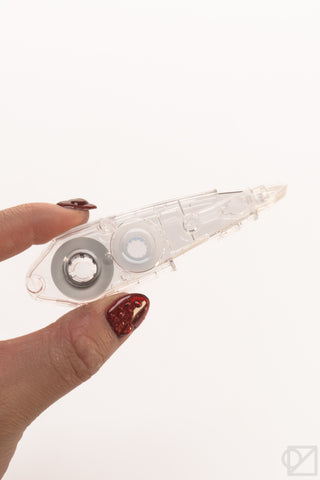 Clear correction tape applicator with blue stripe and circular tape wheel