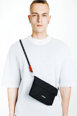 Black rope strap on small crossbody bag, worn over the shoulder