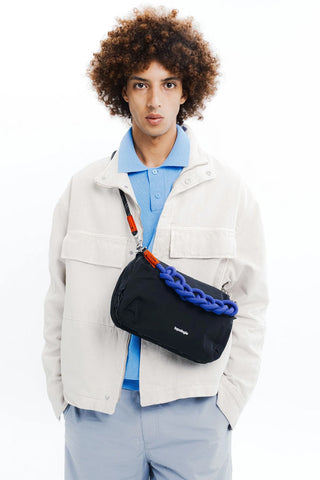 Person wearing bag with black strap and smaller navy rope strap on small crossbody bag, worn across the chest