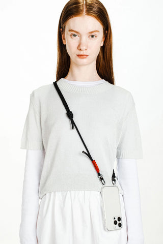 Black rope strap with red accent and clear phone case, worn crossbody