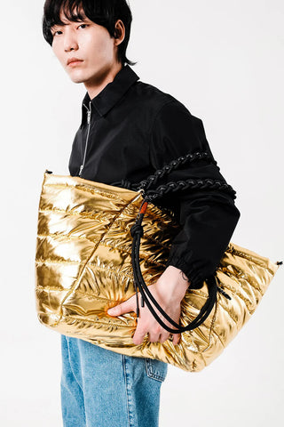 Gold quilted tote with braided rope strap, metal rings, and black end hardware
