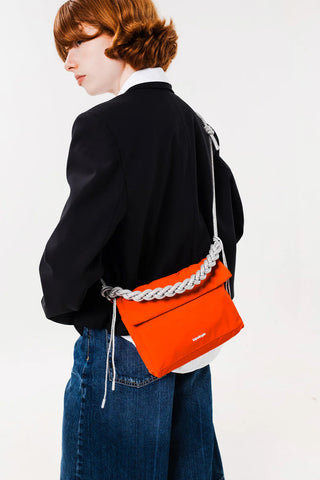 Grey braided rope strap with metal rings and orange tab on orange mini crossbody bag