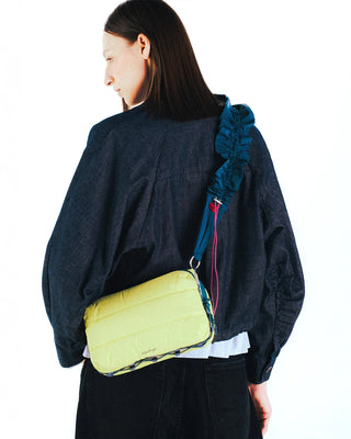 Canary yellow quilted bottle sacoche worn crossbody by model, navy strap visible