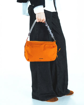 Orange crossbody bottle pouch with metallic strap chain, holds close to body