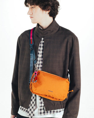 Orange mirror metallic bottle pouch worn crossbody, with blue strap detail and cords