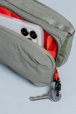 Medium bottle sling bag close-up with bottle compartments and keyring zipper pull