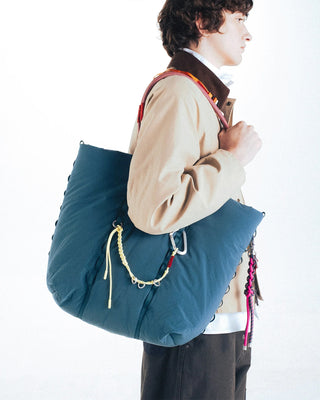 Braided keychain with yellow cords and metal rings on teal tote strap