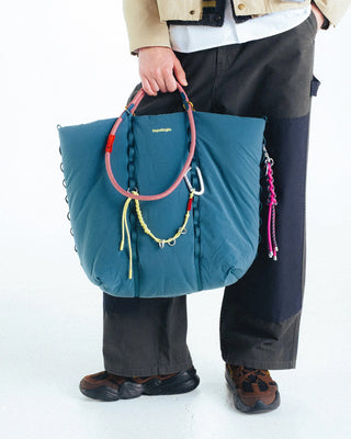 Braided keychain with neon cords and metal rings hanging from bag handle