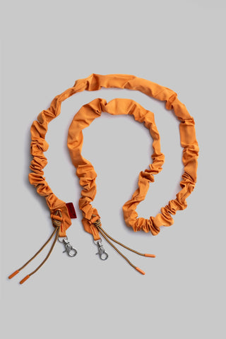 Orange tech sateen bungee strap with ruched elastic and metal clips, two ends