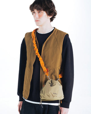 Orange ruched bungee strap worn crossbody on a small bag, elastic ends with clips