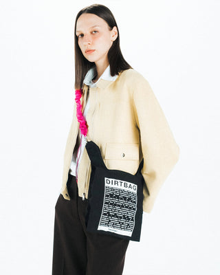Pink bungee strap worn crossbody on a black pouch bag with clip ends