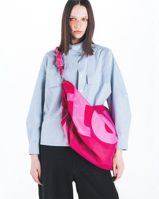 Pink bungee strap draped over a pink tote-style bag with large graphic