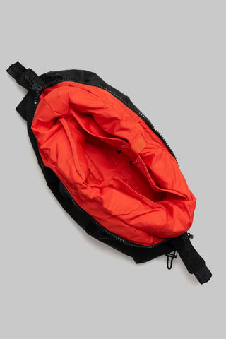 Hobo bag interior close-up with red lining and zipper opening; black strap ends
