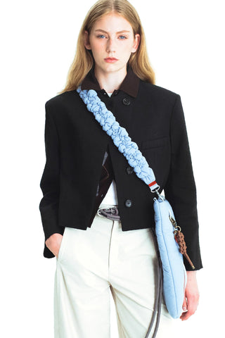 Braided light-blue crossbody strap with metal clips worn on a black jacket