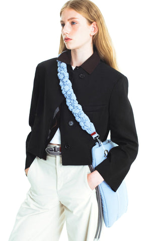 Ruffled light blue shoulder strap with pouch and metal clasp, worn with jacket