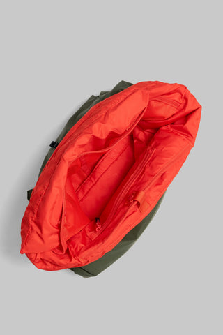 Open deep green nylon helmet bag showing red interior padding and mesh pocket