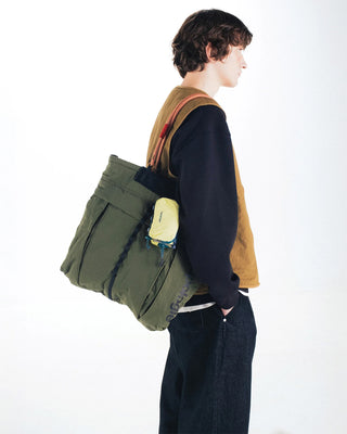 Deep green nylon helmet bag worn on shoulder with front zip pocket and straps