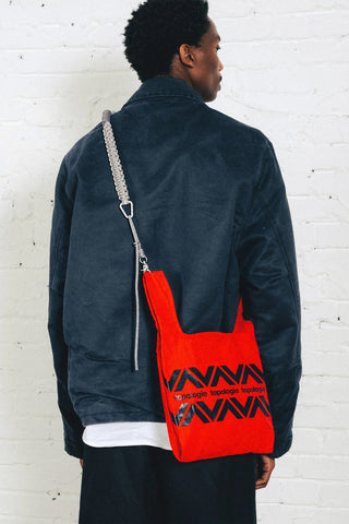 Topologie macrame crossbody strap in gray, worn with a red bag.