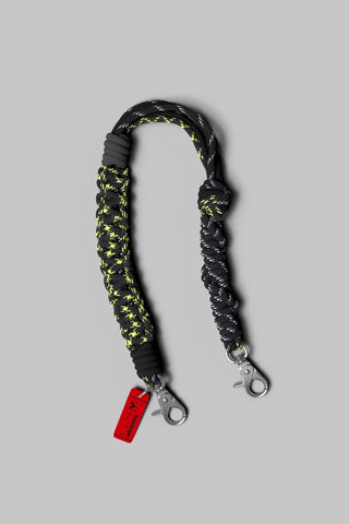 Macrame wrist strap in dark braided cord with neon yellow accents, metal clips
