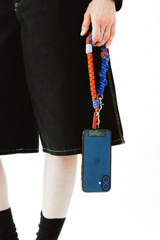 Multicolor macrame wrist strap with metal clips, holding a blue phone case
