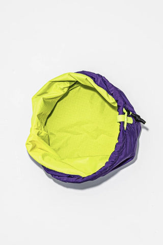 Neon yellow bucket bag with purple interior and drawstring top.