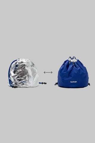 Reversible bucket bag showing metallic silver side and royal blue side