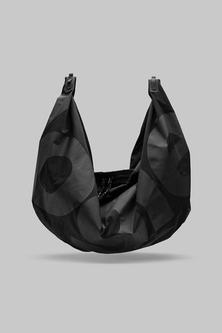 Black crescent hobo bag with dual top handles and circular patch pattern