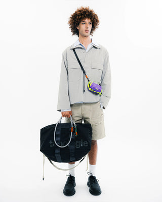 Black duffle bag carried by model with side handles and zip top