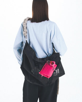 Black large duffle bag worn crossbody with adjustable strap