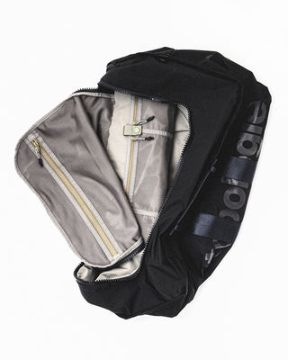 Black duffle bag open end with gray lining, pockets, and zipper closure