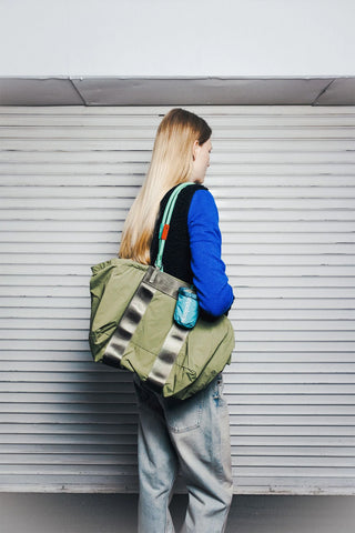 Olive and black duffle bag carried over shoulder with side compartments