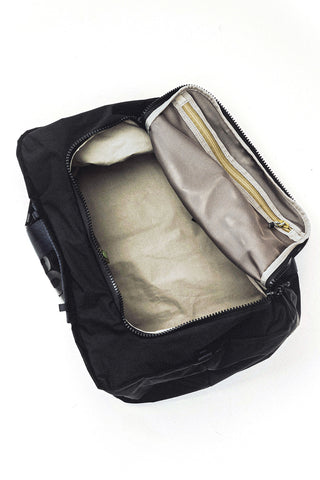 Black duffle bag open to show light interior and zippered mesh pocket
