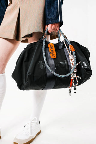 Black medium duffle bag with dual side handles and orange tag