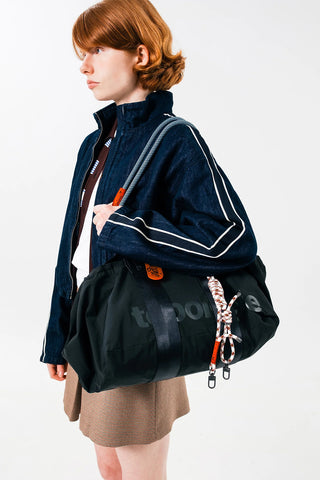 Black medium duffle bag with striped details and side strap on model