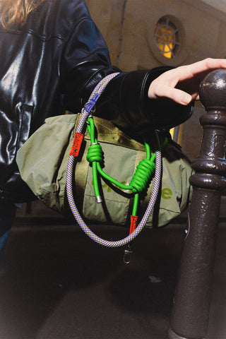 Moss green duffle bag with green and multicolor cord straps and metal rings